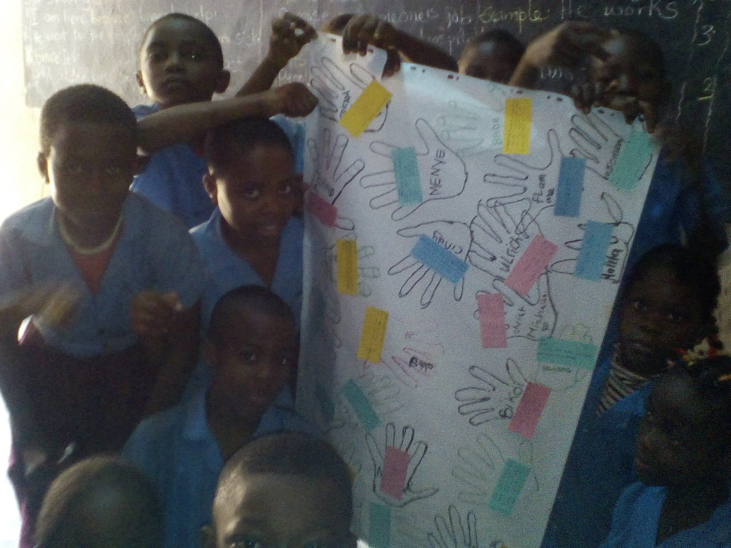 Des enfants devant une affiche ornée d'empreintes de mains colorées