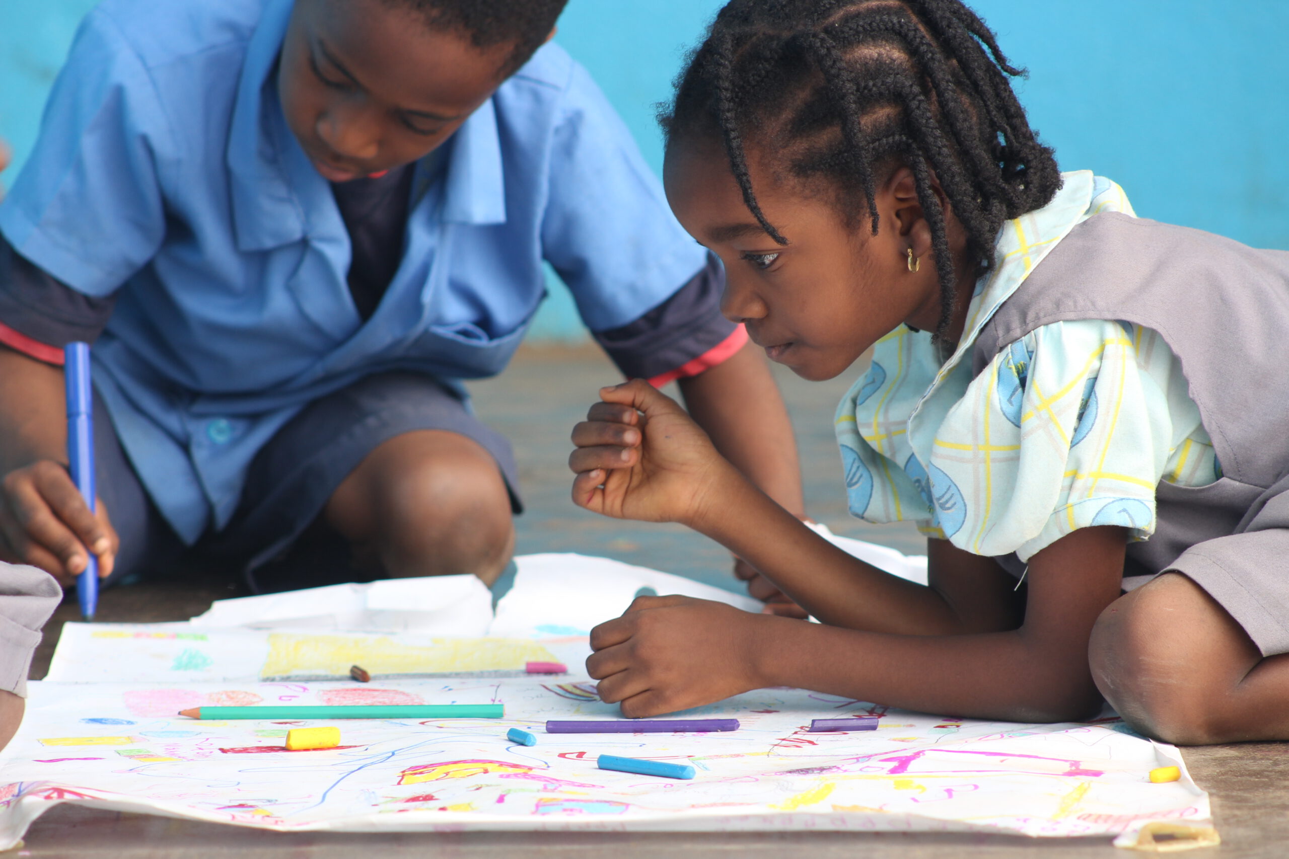 Deux enfants dessinent ensemble sur une grande feuille